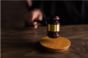  Close-up of a judge’s gavel striking a wooden sound block in a courtroom, symbolizing a legal decision 